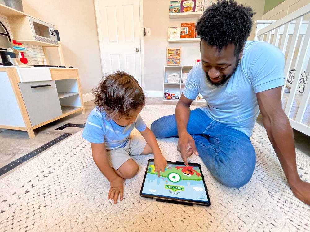 Parent and child using a tablet together on the floor